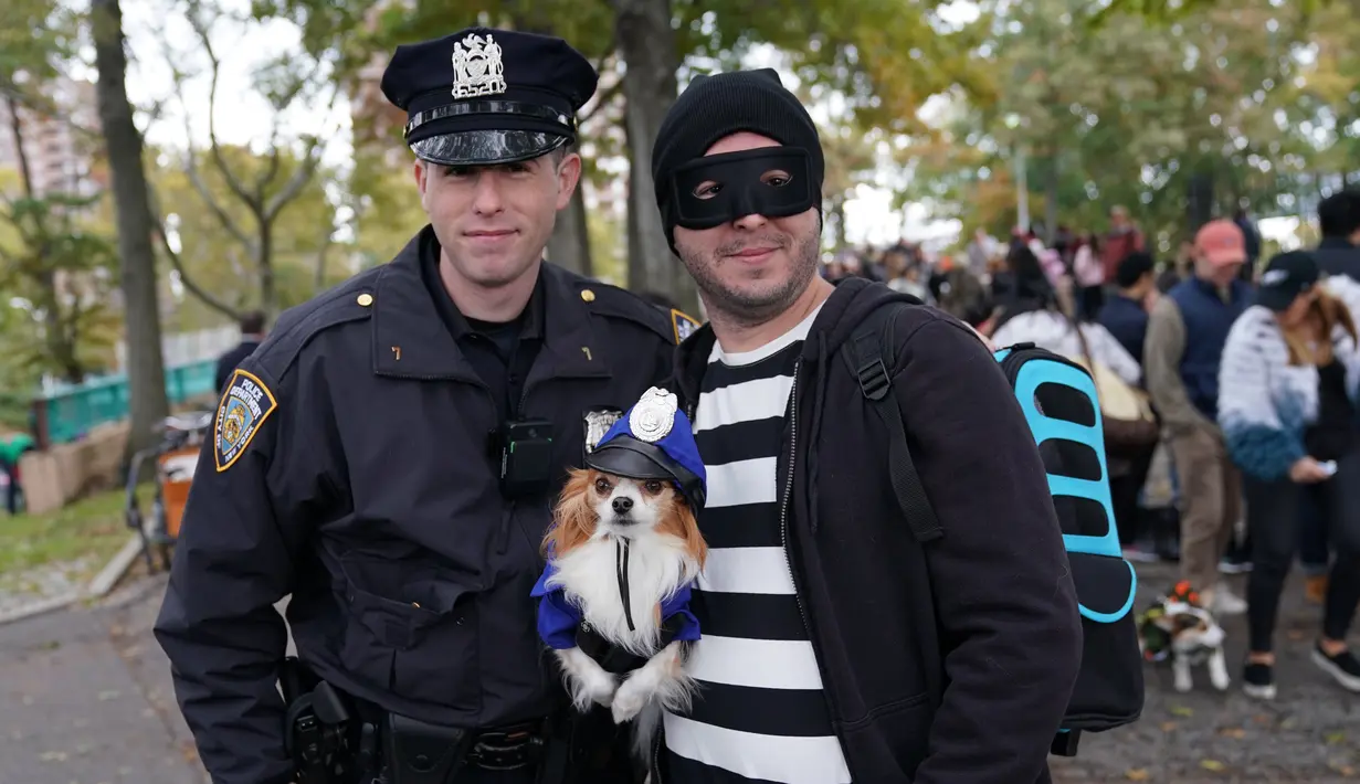 Seekor anjing dan pemiliknya dalam kostum terlihat selama Parade Tompkins Square Halloween Dog di New York, 27 Oktober 2018. Anjing dengan kostum yang paling unik akan dinobatkan sebagai pemenang dan mendapat hadiah dari panitia. (TIMOTHY A. CLARY / AFP)