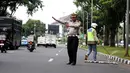 Petugas Polisi menertibkan jalan saat relawan Saber membersihkan ranjau paku di depan Istana Merdeka, Jakarta, Jumat (6/3/2015). Paku yang ditebar oleh orang tidak bertangung jawab seringkali mengganggu para pengguna jalan. (Liputan6.com/Faizal Fanani)