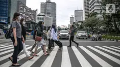 Orang-orang menyeberang jalan dengan latar belakang gedung perkantoran di kawasan Sudirman, Jakarta, Rabu (16/12/2020). Pemprov DKI Jakarta akan mengikuti arahan Wakil Ketua Komite Penanganan Covid-19 Luhut Binsar Pandjaitan terkait pengetatan work from home (WFH). (Liputan6.com/Faizal Fanani)