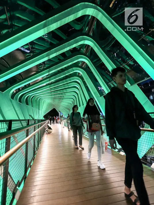 Pejalan kaki melintas di JPO Gelora Bung Karno di Jalan Jend Sudirman, Jakarta, Senin (4/3) malam. JPO tersebut menjadi daya tarik tersendiri bagi pejalan kaki karena desainnya yang artistik dan Instagramable. (Liputan6.com/Fery Pradolo)