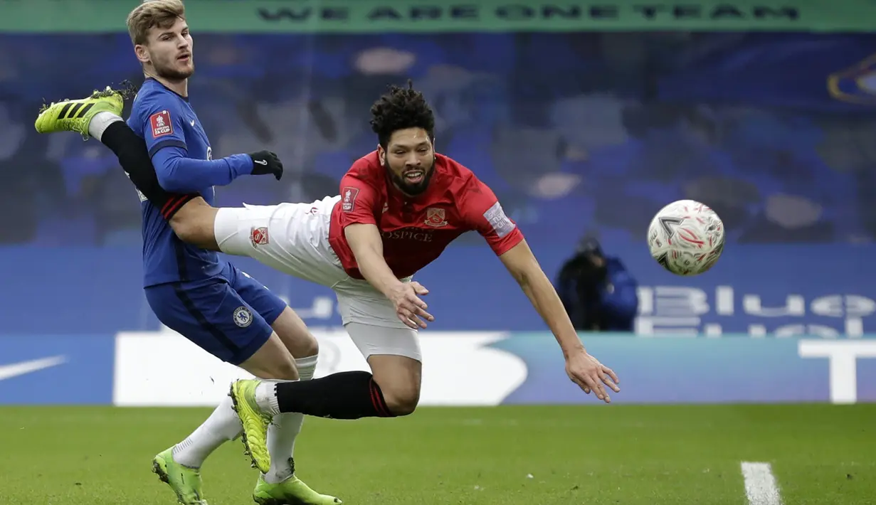 Gelandang tim divisi empat Morecambe, Nathaniel Knight-Percival dan penyerang Chelse, Timo Werner bersaing memperebutkan bola pada babak ketiga Piala FA 2020/21 di Stamford Bridge, Minggu (10/1/2021). Chelsea menggasak Morecambe dengan skor telak 4-0. (AP Photo/Matt Dunham)