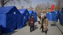 Penduduk yang terkena dampak gempa terlihat di luar tenda-tenda bantuan yang didirikan di sebuah kompleks sekolah di desa Gaoli, Kabupaten Jishishan, Provinsi Gansu, Barat Laut Tiongkok pada 20 Desember 2023. (PEDRO PARDO/AFP)