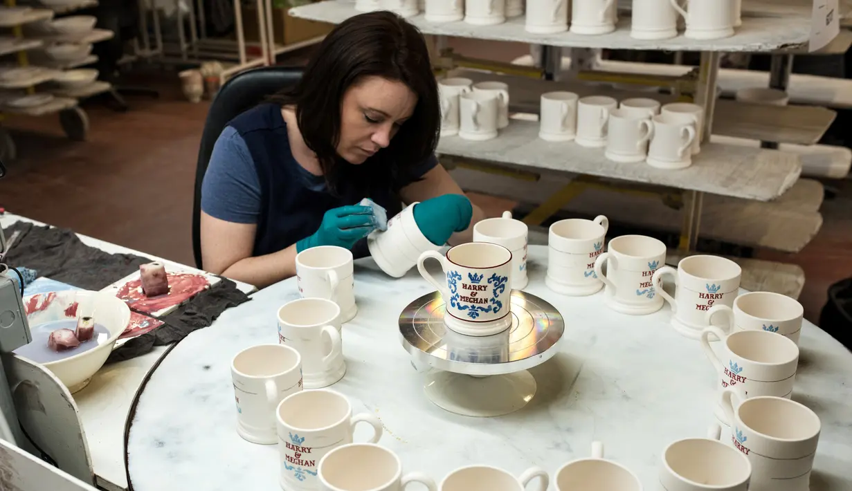 Pekerja melukis dengan tangan sebuah mug untuk merayakan pernikahan Pangeran Harry dan Meghan Markle di pabrik Emma Bridgewater di Stoke-on-Trent, Inggris (16/4). (AFP/Oli Scarff)