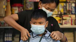 Seorang wanita membantu siwa bersiap untuk hari pertama kelas tatap muka di sekolah dasar Comembo di kota Makati, Filipina, Senin (6/12/2021). Beberapa sekolah di Manila diizinkan dibuka kembali setelah berbulan-bulan lamanya karena kasus COVID-19 terus menurun. (AP Photo/Aaron Favila)