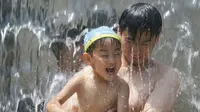 Seorang ayah menggendong anaknya saat bermain air di sebuah taman, Tokyo, (16/7). Badan Meteorologi mengatakan gelombang panas terus berlanjut di wilayah metro ketika suhu naik mencapai 35 derajat Celcius (95 derajat Fahrenheit). (AP Photo/Koji Sasahara)