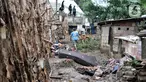 Warga berjalan di dekat tanggul batang pohon yang berada di bantaran Kali Ciliwung, Rawajati, Jakarta, Minggu (5/1/2020). Tanggul dari kayu dolken dan karung pasir yang baru dibangun pada akhir Desember 2019 itu rusak hingga dipenuhi sampah akibat terjangan arus banjir. (merdeka.com/Iqbal Nugroho)