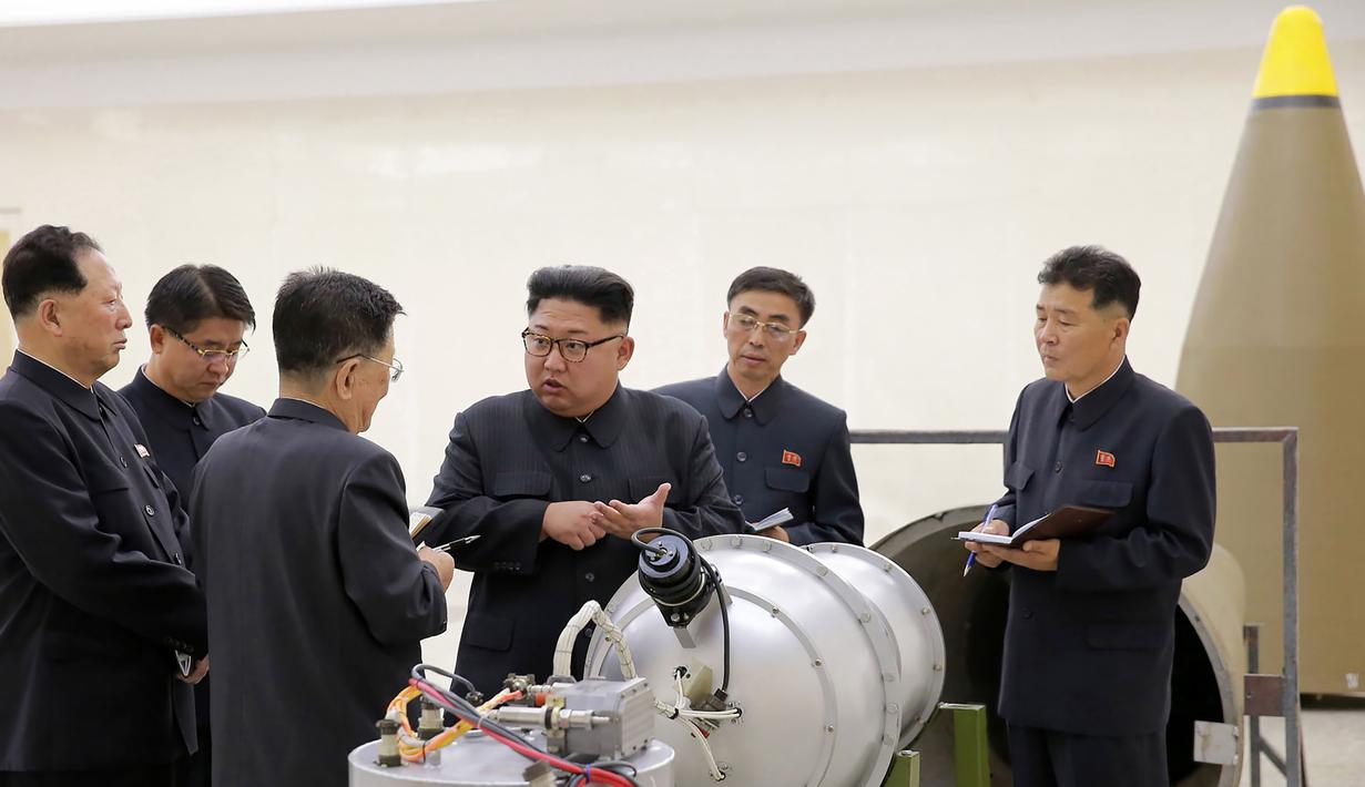 Pemimpin Korut, Kim Jong-un berbincang dengan para peneliti mengenai program senjata nuklir saat meninjau pembuatan bom hidrogen yang dapat dimasukkan ke dalam rudal balistik antarbenua pada 3 September 2017. (AFP Photo/Kcna Via Kns/Str)
