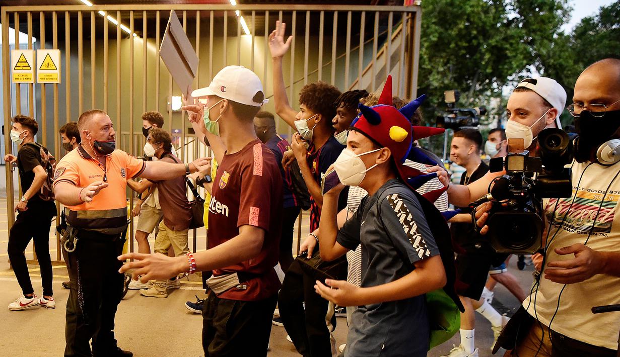 Suporter berusaha menerobos kantor Barcelona saat melakukan aksi, Rabu (26/8/2020). Dalam aksi tersebut fans meminta Lionel Messi bertahan dan menuntut Josep Maria Bartomeu mundur dari jabatannya. (AFP/Pau Barrena)
