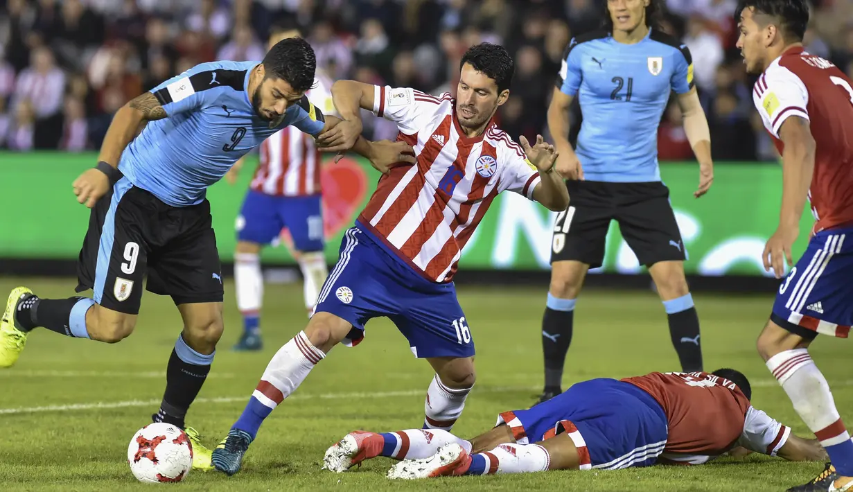 Striker Uruguay, Luis Suarez, berebut bola dengan gelandang Paraguay, Cristian Riveros, pada laga kualifikasi piala dunia 2018 di Stadion Defensores del Chaco, Rabu (6/9/2017). Uruguay menang 2-1 atas Paraguay. (AFP/Daniel Duarte)
