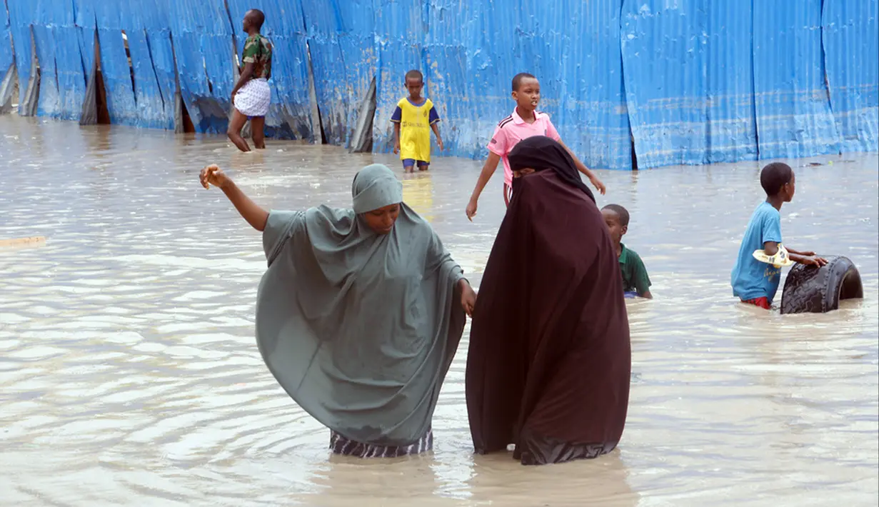Wanita Somalia berjalan melewati air banjir saat hujan lebat di Mogadishu, Somalia, 20 November 2023. Banjir terburuk yang melanda Somalia dalam beberapa dekade telah menewaskan banyak orang dan memaksa ribuan orang meninggalkan rumah mereka. (AP Photo/Farah Abdi Warsameh)