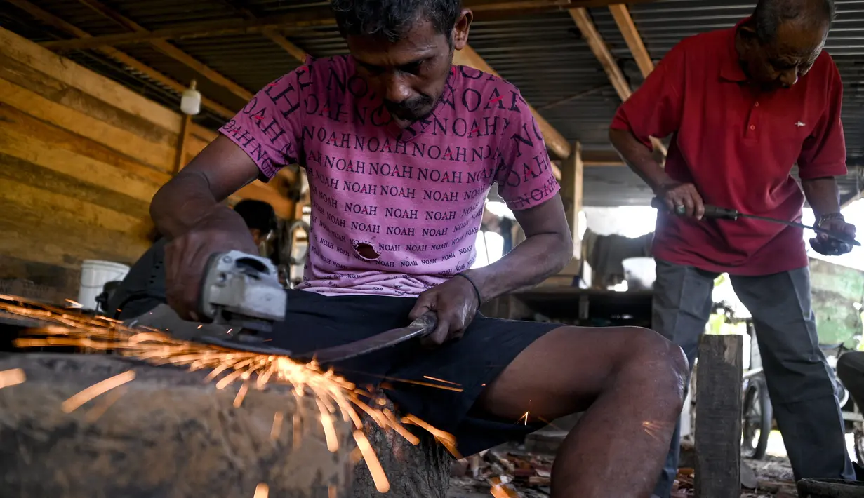 Pandai besi menggunakan penggiling untuk membuat pisau di sebuah bengkel di Sibreh, provinsi Aceh (5/10/2021). Menurut catatan sejarah, Rencong adalah senjata yang digunakan Kesultanan Aceh sejak masa pemerintahan Sultan Ali Mughayat Syah yang merupakan Sultan Aceh pertama. (AFP/Chaideer Mahyuddin)
