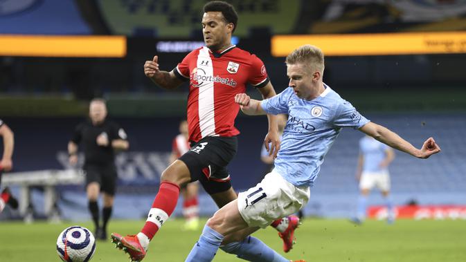 Ryan Bertrand dari Southampton dan Oleksandr Zinchenko dari Manchester City berebut bola pada pertandingan Liga Inggris di Stadion Etihad di Manchester, Inggris, Rabu, 10 Maret 2021. (Clive Brunskill / Pool via AP )