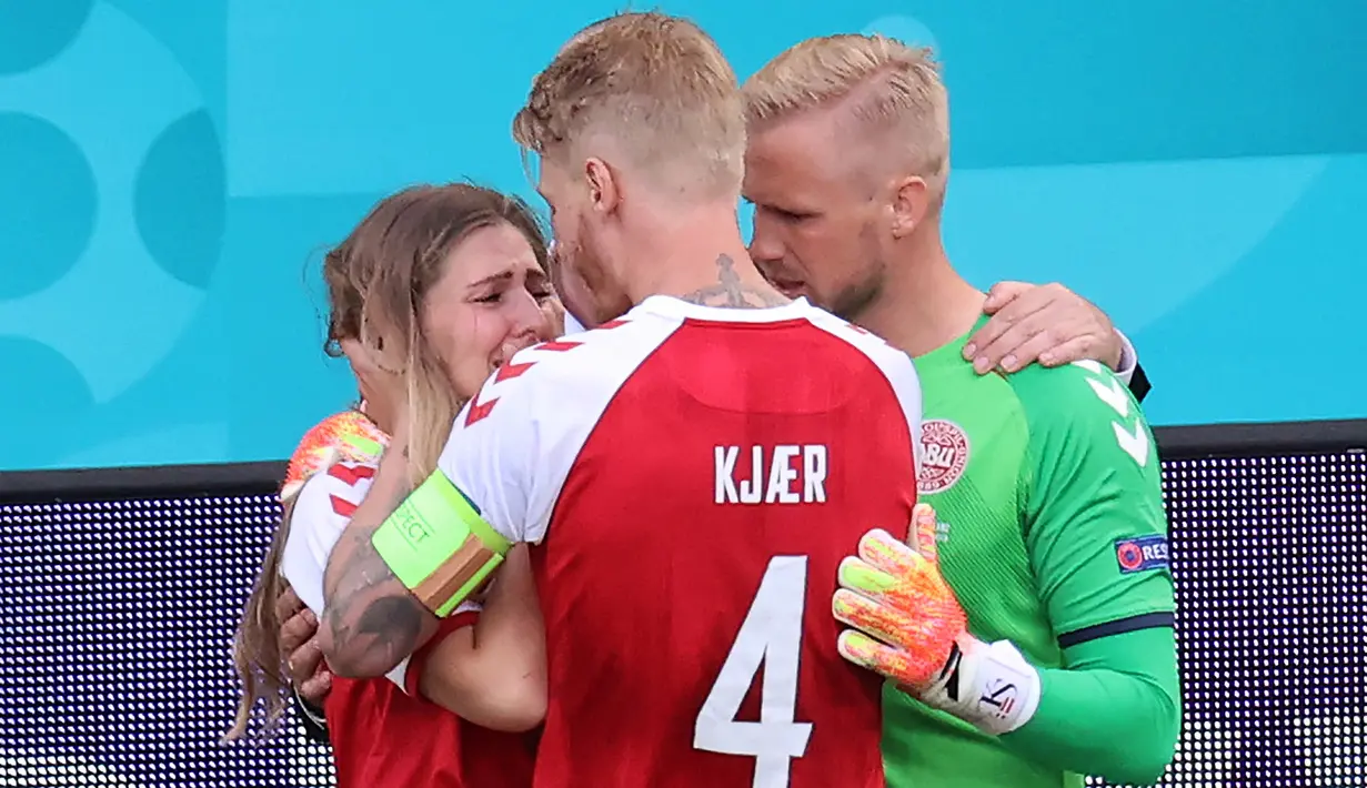 Pemain Denmark, Kasper Schmeichel (kanan) dan Simon Kjaer (tengah) menghibur Sabrina Kvist Jensen, kekasih gelandang Denmark, Christian Eriksen setelah pingsan di lapangan pada laga Denmark vs Finlandia di Grup B Euro 2020 di Parken Stadium, Copenhagen, Sabtu (12/6/2021). (WOLFGANG RATTAY/AFP/POOL)