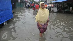 Seorang wanita melintas saat banjir melanda kawasan Rawa Buaya, Jakarta, Minggu (28/2/2016). Rawa Buaya menjadi kawasan banjir terparah hingga mencapai 1 meter. (Liputan6.com/Gempur M Surya)