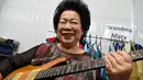 Mary Ho (81) berpose dengan gitar elektriknya saat melakukan latihan di Singapura, 5 Agustus 2017. Wanita yang dikenal sebagai Nenek Maria itu baru belajar gitar pada usia 60 tahun setelah sejak lama memimpikan belajar alat musik ini. (Roslan RAHMAN/AFP)