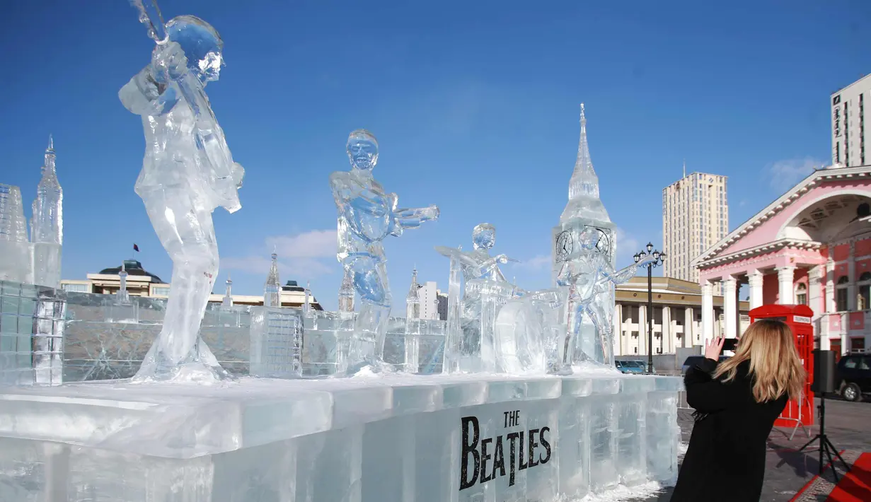Dubes Inggris Katrin Arnold mengambil gambar patung es the Beatles dan Big Ben London di Ulaanbaatar, Mongolia (23/1). Patung dibuat untuk menandai ulang tahun ke-55 pembentukan hubungan diplomatik antara kedua negara. (AFP Photo/Byambasuren Byamba-Ochir)