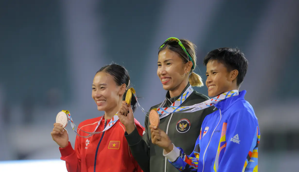 Diketahui, Emilia Nova terakhir kali meraih emas heptathlon pada 2017. Tampak dalam foto, atlet atletik Indonesia, Emilia Nova (tengah) usai prosesi pengalungan medali usai memenangi lomba dan meraih emas nomor heptathlon (tujuh lomba) SEA Games 2025 di Stadion Supachalasai Bangkok, Thailand Selasa (16/12/2025) malam. (Bola.com/Bagaskara Lazuardi)