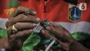 Seto Krisna Putra (39) menyelesaikan pembuatan miniatur robot dari sampah korek gas di Kantor Sudin LH Jakarta Timur, Minggu (20/2/2022). Seto menyulap sampah korek gas dari bertugas menjadi miniatur robot beragam karakter bernilai jual tinggi. (merdeka.com/Iqbal S Nugroho)