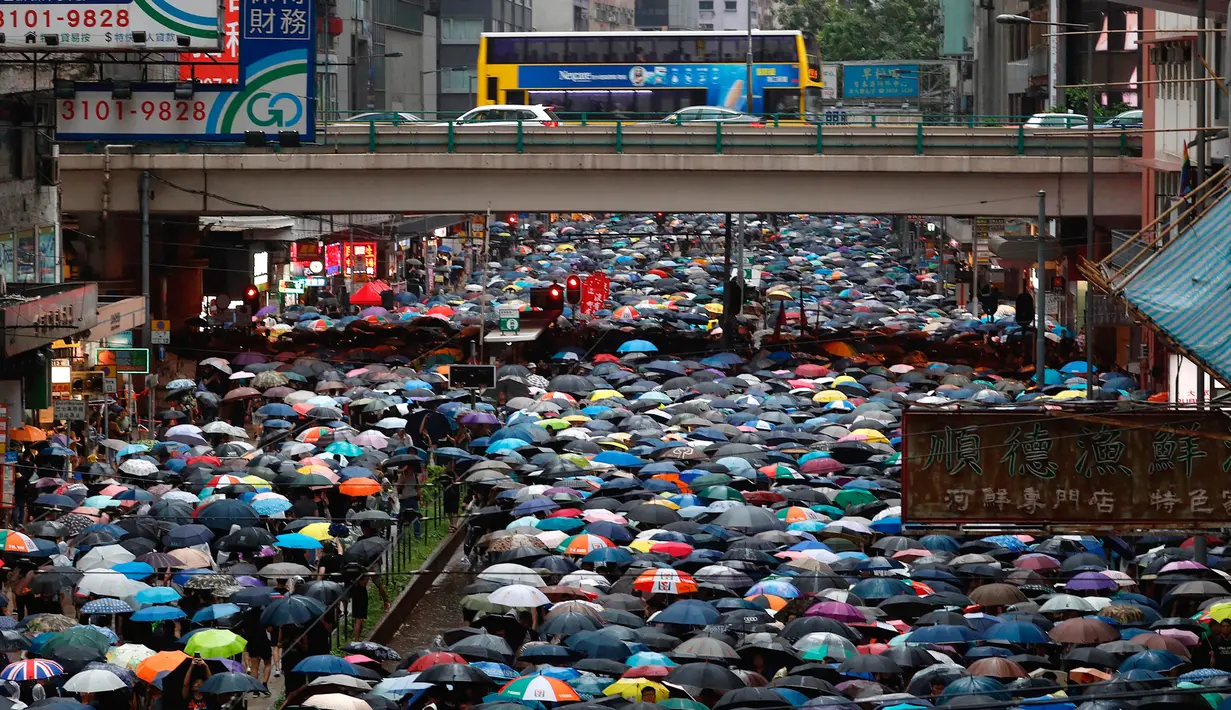 Pengunjuk rasa membawa payung saat menuju Victoria Park, Hong Kong, Minggu (18/8/2019). Puluhan ribu massa pro-demokrasi membawa payung saat hujan mengguyur Victoria Park dan sekitarnya. (AP Photo/Vincent Yu)