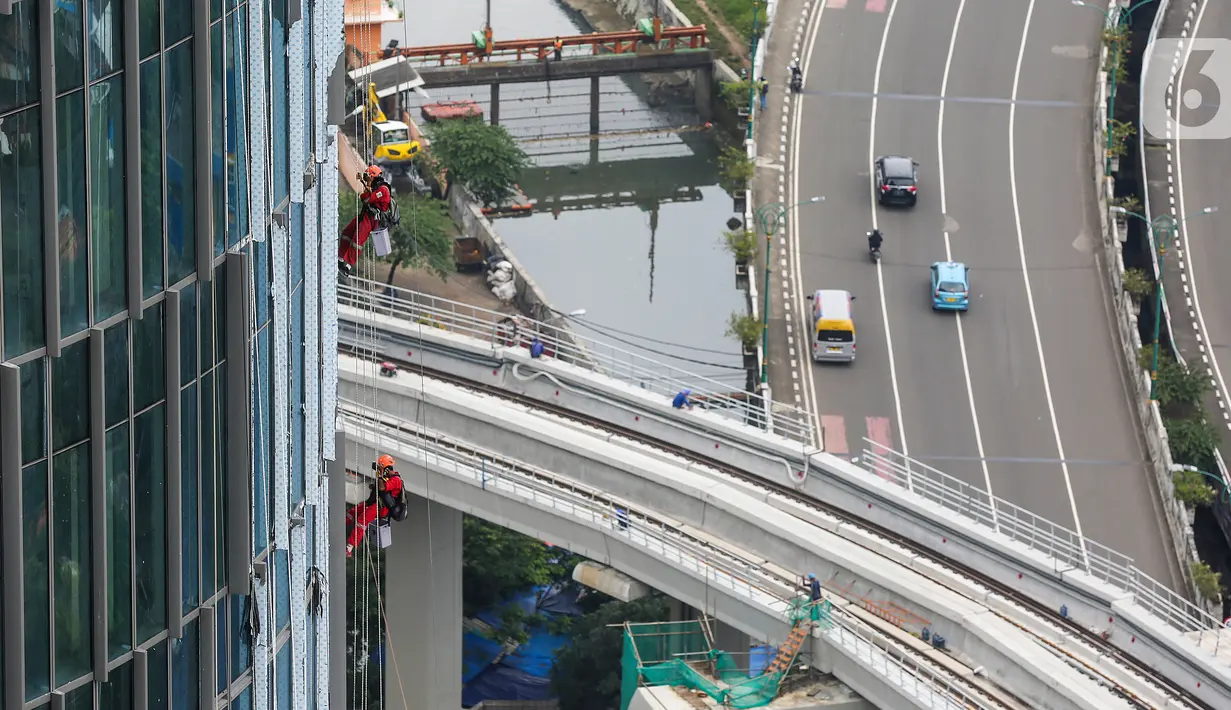 Pekerja membersihkan kaca gedung bertingkat di Jakarta, Jumat (26/02/2021). BP Jamsostek menekankan dua aspek penting terkait pandemi Covid-19, yakni isu kesehatan dan perekonomian dengan jaminan sosial bagi para pekerja dan penerapan K3. (Liputan6.com/Fery Pradolo)