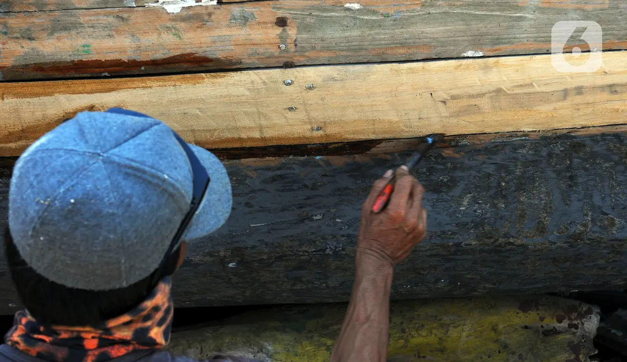 Tukang kayu memperbaiki kapal motor di Pelabuhan Kalibaru, Jakarta, Rabu (8/3/2023). Untuk perbaikan satu unit kapal motor nelayan tradisional membutuhkan biaya sekitar Rp 100 juta. (merdeka.com/Imam Buhori)