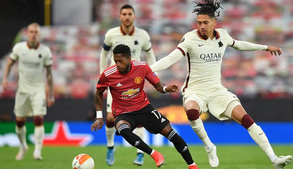 Gelandang Manchester United, Fred (kiri) menguasai bola dibayangi bek AS Roma, Chris Smalling dalam laga leg pertama semifinal Liga Europa 2020/2021 di Old Trafford Stadium, Manchester, Kamis (29/4/2021). Manchester United menang 6-2 atas AS Roma. (AFP/Paul Ellis)