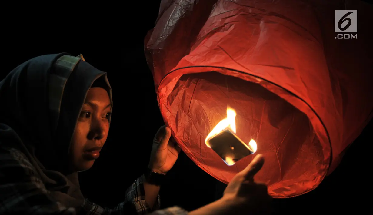 Pengunjung menyalakan api sebelum menerbangkan lampion saat perayaan Tahun Baru Imlek di Pantai Lagoon, Ancol, Jakarta, Selasa (5/2) malam. Sebanyak 500 lampion dilepas dalam  rangka menutup Festival Imlek di Ancol. (Merdeka.com/Iqbal S Nugroho)