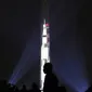 Orang-orang menyaksikan proyeksi roket NASA, Saturn V, di Monumen Washington menandai peringatan 50 tahun misi Apollo 11 ke bulan di National Mall, Washington, Selasa (16/7/2019). Pada 16 Juli 1969, NASA mencatatkan sejarah dengan melakukan peluncuran Apollo 11. (Mark Wilson/Getty Images/AFP)