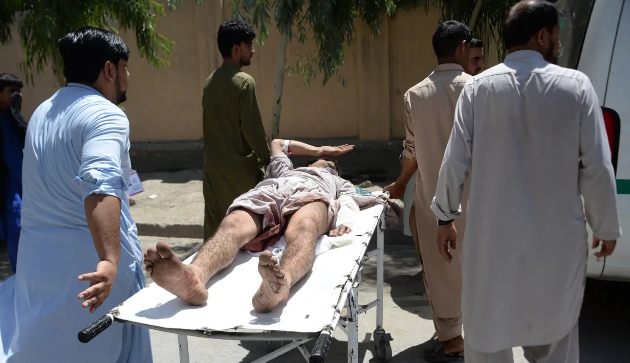Seorang pria Afghanistan yang terluka dibawa dengan tandu oleh para sukarelawan di dekat lokasi ledakan bom bunuh diri dan serangan bersenjata di Jalalabad, Selasa (31/7). Sebanyak 15 orang tewas akibat insiden tersebut. (AFP/NOORULLAH SHIRZADA)