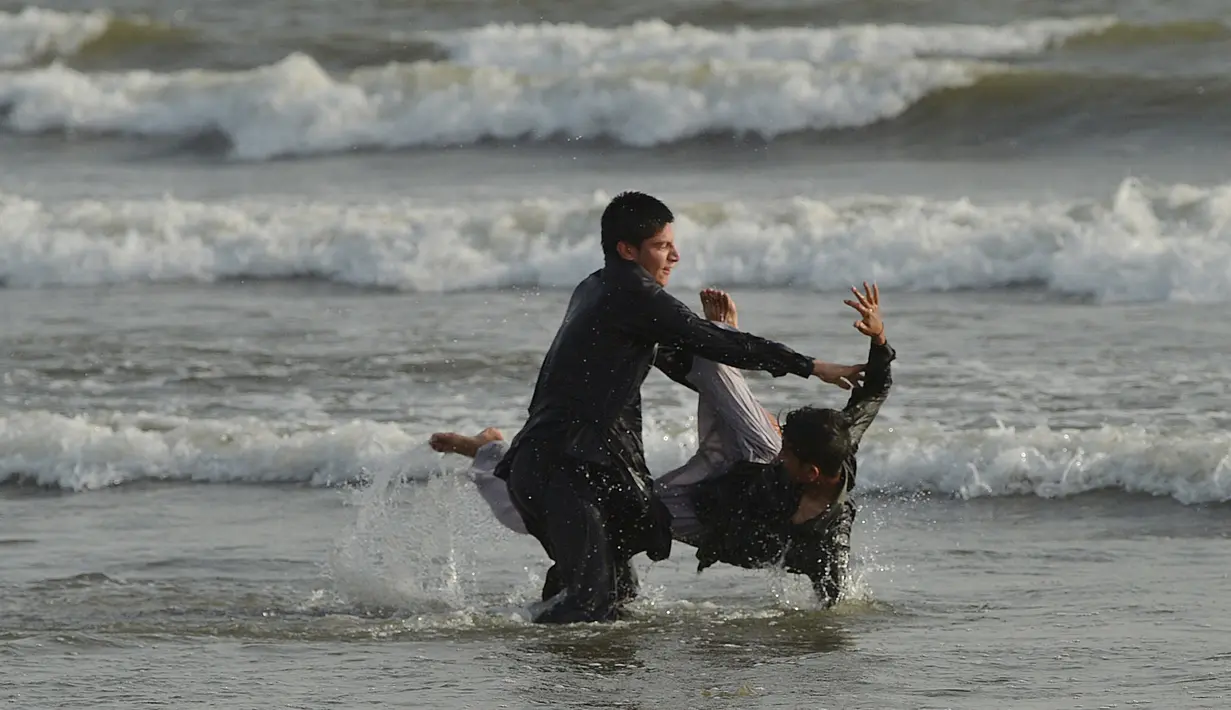 Dua anak Pakistan bermain di pantai Clifton selama gelombang panas yang terjadi di Karachi, Senin (21/5). Suhu di Karachi, pada Senin, menyentuh 43 derajat celsius, dan diperkirakan akan bertahan hingga tiga hari mendatang. (AFP/RIZWAN TABASSUM)