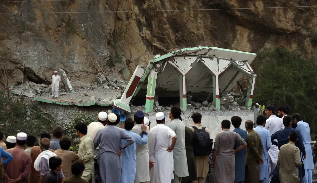 Orang-orang berdiri dan menyaksikan masjid yang rusak setelah serangan bom bunuh diri di dalam masjid pinggir jalan di distrik Khyber di provinsi Khyber Pakhtunkhwa, Pakistan, Selasa, 25 Juli 2023. (AP Photo/Muhammad Sajjad)