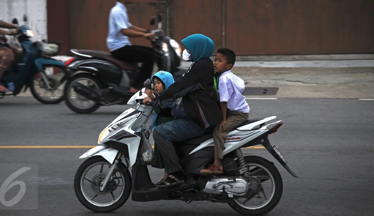 Seorang wanita mengenakan masker saat mengendarai motor bersama anak-anaknya di Narathiwat, Thailand, Senin (5/10/2015). Kabut asap dari kebakaran hutan di Indonesia kini menyelimuti provinsi di wilayah selatan Thailand. (AFP PHOTO/Madaree TOHLALA)