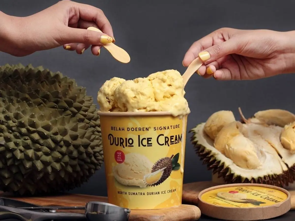 Mangkuk penuh es durian yang lezat, disajikan dengan irisan durian segar dan daun mint sebagai hiasan, siap dinikmati di hari yang panas