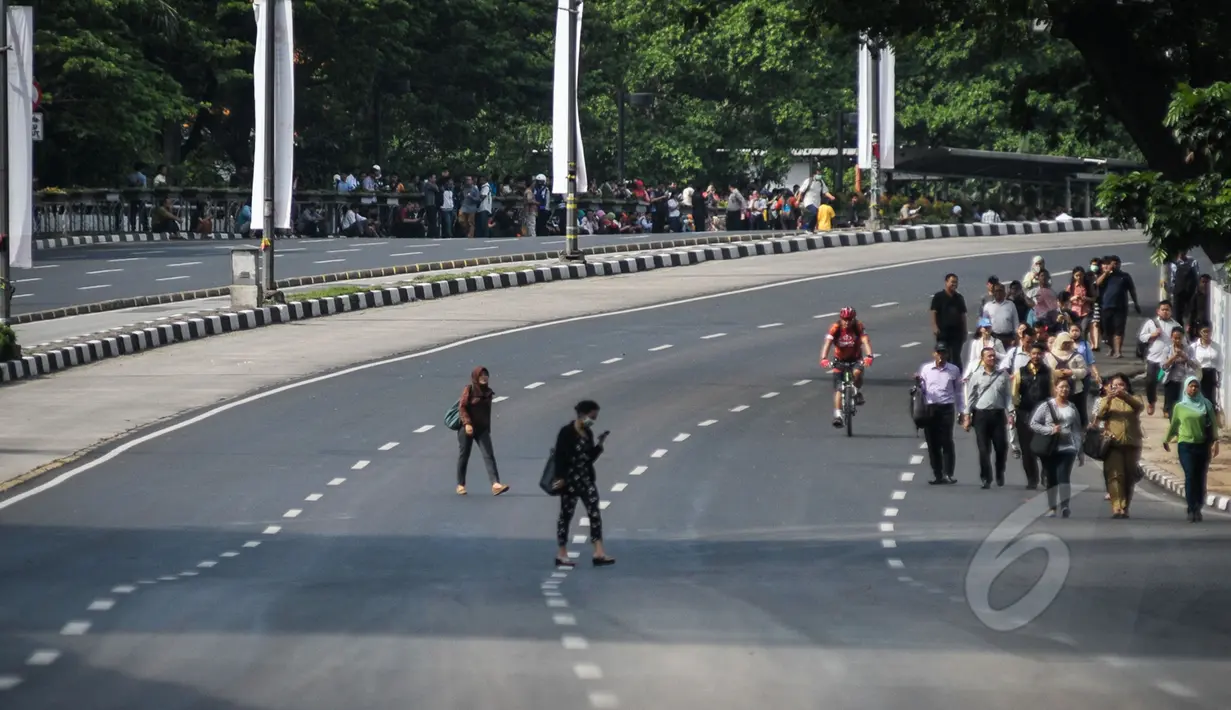 Sejumlah karyawan berjalan kaki untuk menuju kantornya di sekitar kawasan Bundaran HI, Jakarta, Rabu (22/4/2015). Sejumlah jalan utama di Jakarta ditutup total untuk sementara waktu terkait puncak Konferensi Asia-Afrika (KAA). (Liputan6.com/Faizal Fanani)