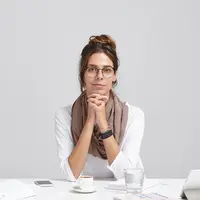Seorang perempuan sedang menopang dagunya dengan kedua tangan (Foto Dok: Freepik/wayhomestudio).