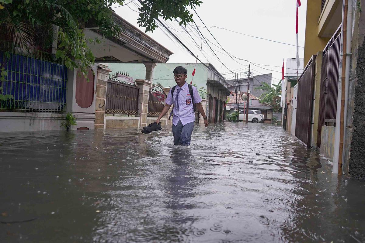 FOTO: Drainase Meluap, Warga Pasar Rebo Terobos Genangan