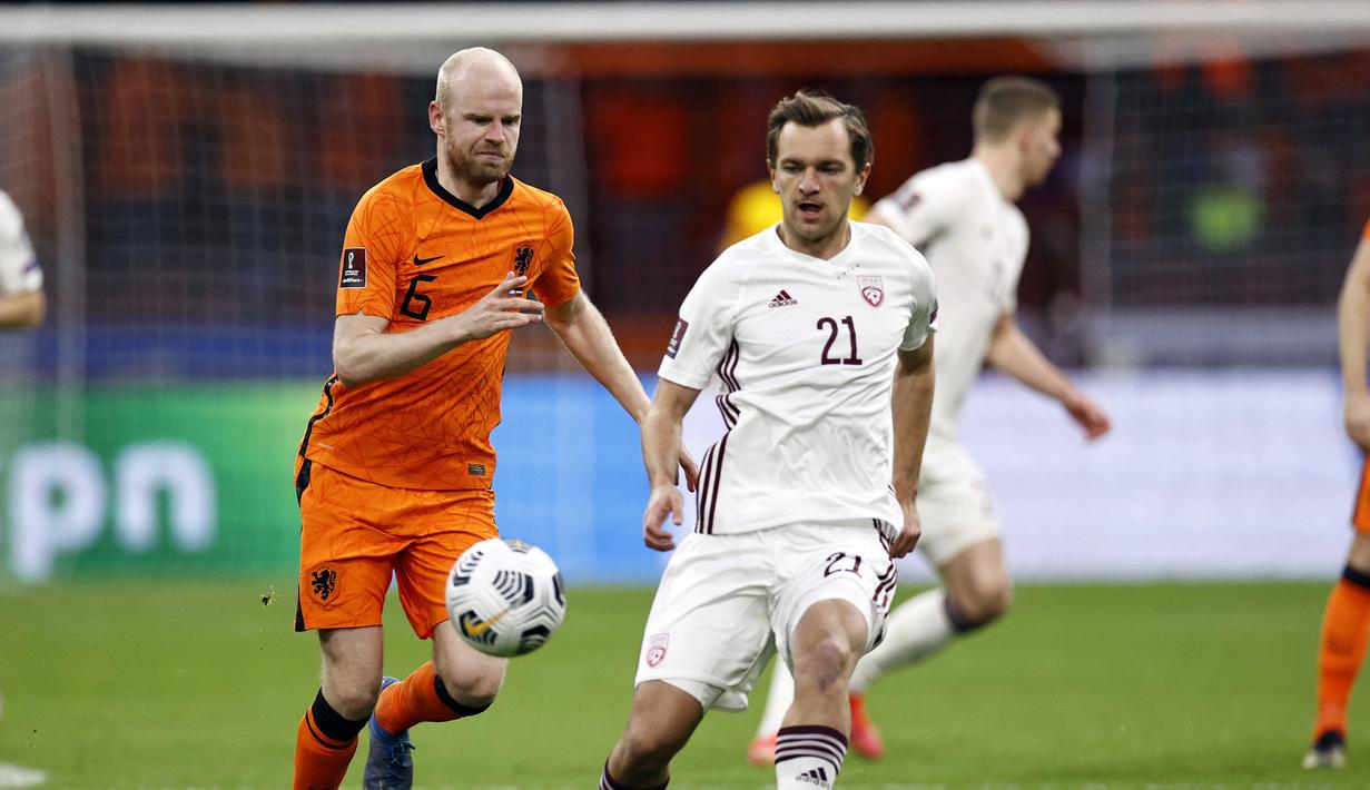 Gelandang Belanda, Davy Klaassen (kiri) berebut bola dengan gelandang Latvia, Kriss Karklins dalam laga Kualifikasi Piala Dunia 2022 Zona Eropa Grup G di Johan Cruijff Arena, Amsterdam, Sabtu (27/3/2021). Belanda menang 2-0 atas Latvia. (AFP/Maurice van Steen/ANP)