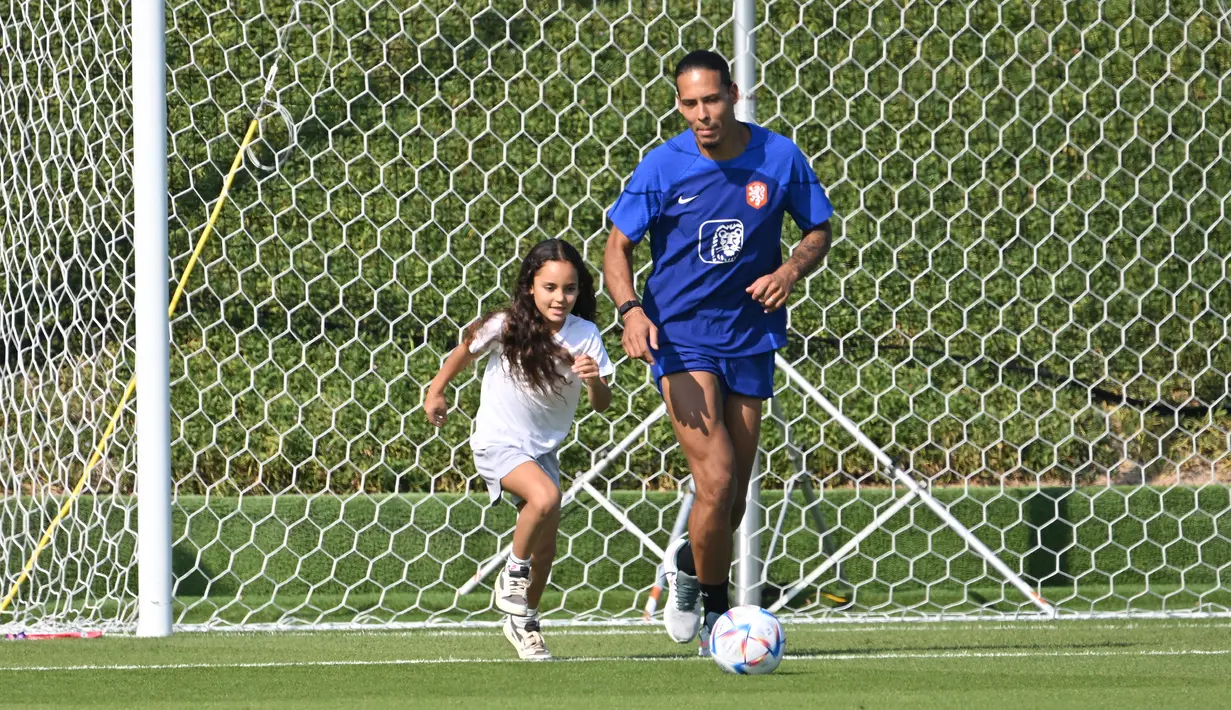 <p>Bek Timnas Belanda Virgil van Dijk bermain dengan putrinya usai latihan di tempat latihan Universitas Qatar, Doha, Qatar, Selasa (22/11/2022). Van Dijk memanfaatkan momen pertemuan kerabat dengan menghabiskan waktu bersama anak dan teman-temannya. (Alberto PIZZOLI/AFP)</p>