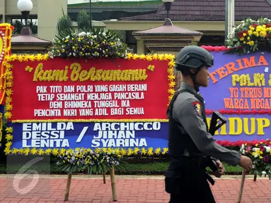 Petugas melintasi deretan karangan bunga yang diletakkan di depan Mabes Polri, Jakarta, Rabu (3/5). Ratusan karangan bunga itu terus berdatangan dan mengelilingi gedung Mabes Polri di Jalan Trunojoyo Jakarta Selatan. (Liputan6.com/Helmi Fithriansyah)