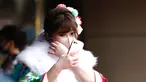 Seorang wanita berusia 20 tahun mengenakan kimono menunggu di pintu masuk Todoroki Arena untuk menghadiri upacara perayaan "Coming-of-Age Day" di Kawasaki, prefektur Kanagawa (11/1/2021). Acara ini digelar dalam keadaan darurat karena Covid-19 pandemi virus corona. (AFP/Behrouz Mehri)