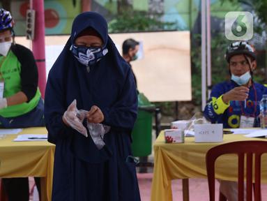 Pemiilih mengenakan sarung tangan plastik saat menggunakan hak suaranya dalam Pilkada Tangerang Selatan di TPS 23 Pondok Jagung Timur, Rabu (9/12/2020). Menggunakan masker hingga memakai sarung tangan plastik menjadi hal wajib saat melakukan pencoblosan di Pilkada 2020. (Liputan6.com/Angga Yuniar)