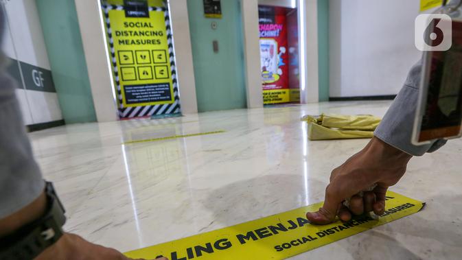 Pekerja memasang stiker saling menjaga jarak di depan lift Lippo Mall Puri, Jakarta, Rabu (3/6/2020). Lippo Malls Indonesia (LMI) menyiapkan prosedur dengan menerapkan protokol kesehatan menuju new normal di seluruh mal di 34 kota besar di Indonesia. (Liputan6.com/Fery Pradolo)