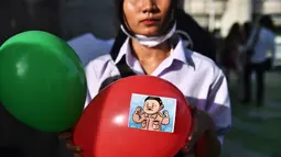 Seorang pengunjuk rasa memegang balon, dengan stiker yang menggambarkan Perdana Menteri Thailand Prayut Chan-O-Cha sebagai Adolf Hitler, selama demonstrasi menentang usulan pembelian kapal selam oleh pemerintah yang berpihak pada militer di Bangkok (31/8/2020). (AFP/Lillian Suwanrumpha)