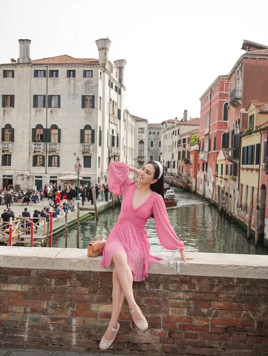 Gaya cantik Shandy Aulia ketika berada di Italia. Ia mengenakan dress selutut berwarna merah muda yang manis. Dress ini memiliki detail garis leher yang dalam dan lengan panjang. [Foto: Instagram/shandyaulia]