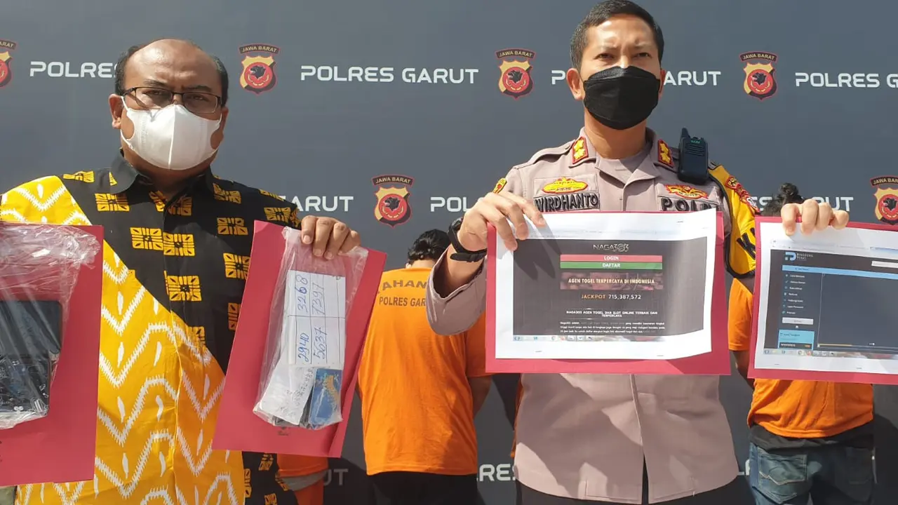 Kapolres Garut AKBP Wirdhanto Hadicaksono didampingi Kasatreskirim AKP Dede Sopandi menunjukan beberapa barang bukti pengungkapan kasus judi online di Garut. (Liputan6.com/Jayadi Supriadin)