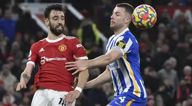 Gelandang Manchester United (MU) Bruno Fernandes berebut bola dengan bek Brighton & Hove Albion Adam Webster pada laga pekan ke-18 Liga Inggris di Old Trafford, Rabu dini hari WIB (16/2/2022). MU menang dengan skor meyakinkan 2-0. (AP Photo/Rui Vieira)