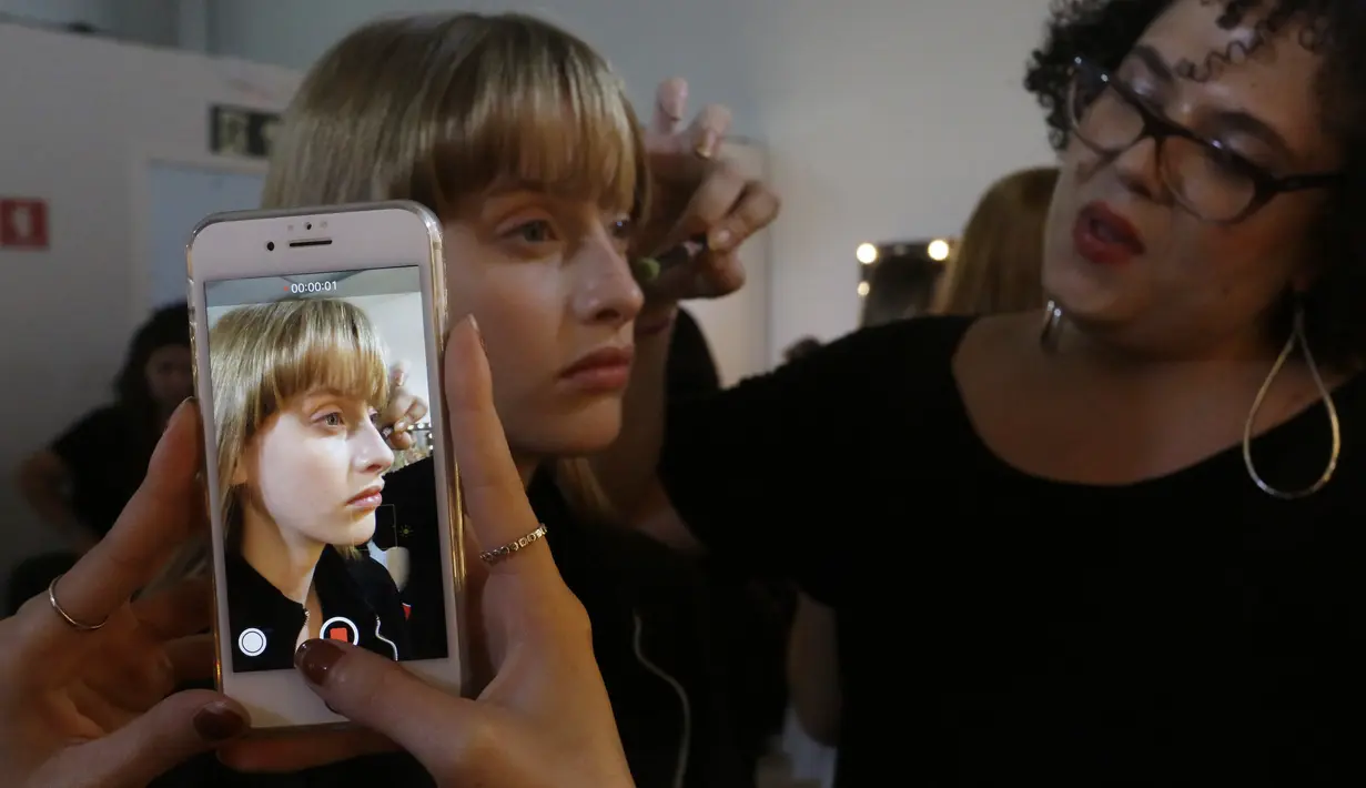 Model saat dirias wajahnya di belakang panggung sebelum tampil membawakan busana koleksi Beira selama Sao Paulo Fashion Week di Sao Paulo, Brasil (16/10/2019). SPFW ke-48 akan berlangsung hingga 18 Oktober.  (AP Photo / Nelson Antoine)