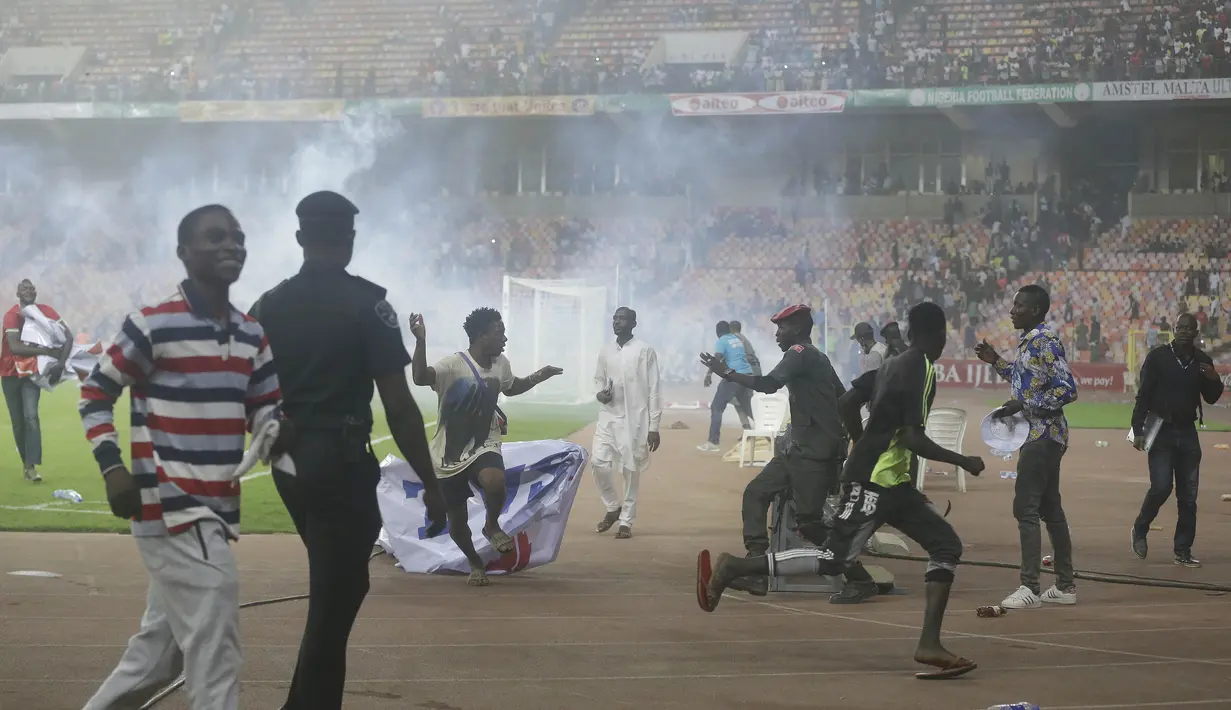 Pihak keamanan stadion pun membalas ulah suporter dengan menembakkan gas air mata untuk memukul balik para suporter. (AP/Sunday Alamba)