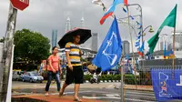 Warga berjalan di samping bendera partai politik dekat Menara Kembar Petronas, Kuala Lumpur, Malaysia, Senin (7/5). Malaysia akan melangsungkan pemilu pada 9 Mei 2018. (AP Photo/Aaron Favila)