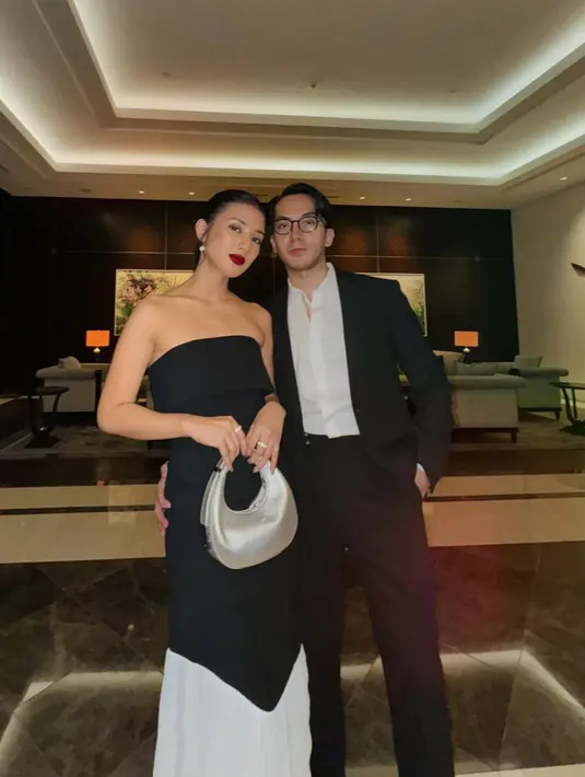 Fita Anggriani dan sang suami kompak kenakan busana monokrom. Fita tampil elegan dengan dress strapless-nya, sedangkan suaminya terlihat gagah dengan setelan jas hitam. [@fitaanggriani].
